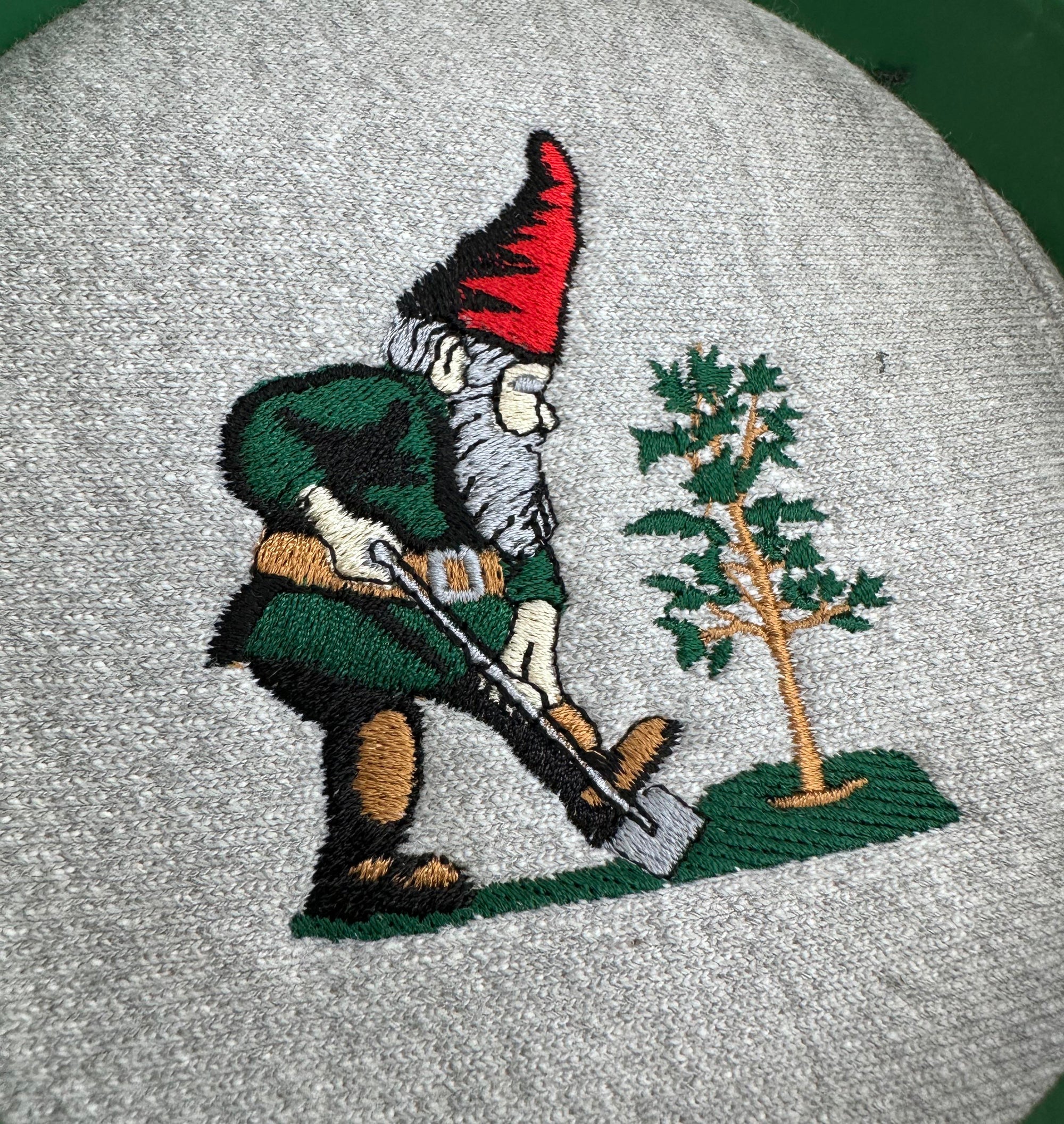 Embroidery of a green garden gnome for a landscaping company on a grey sweater